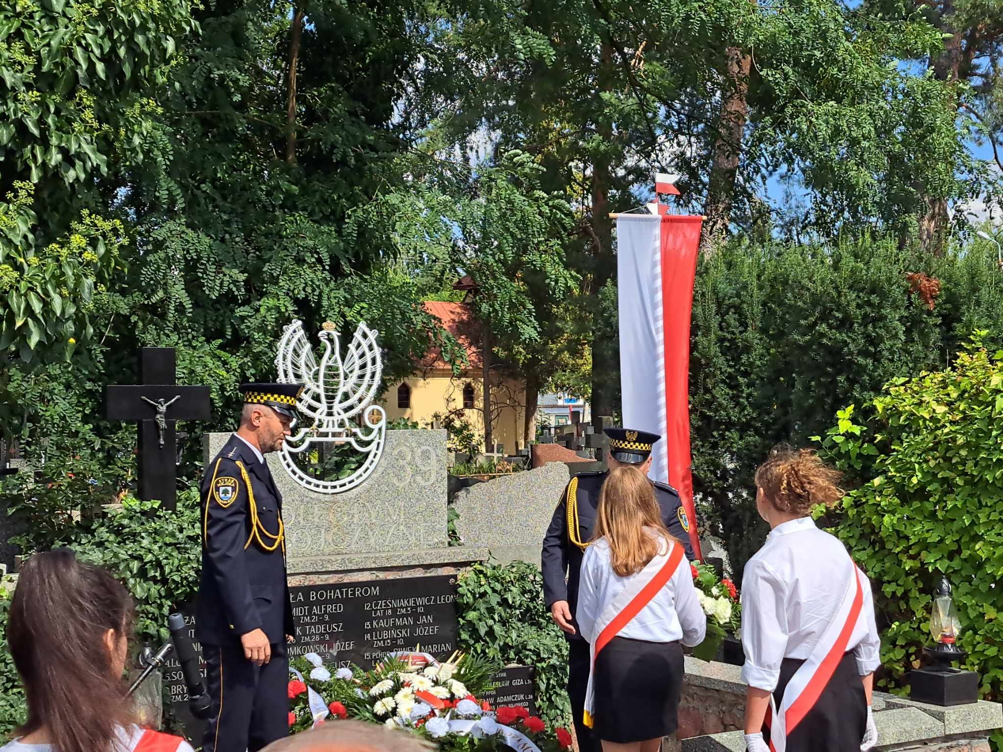 Uczennice składają kwiaty na grobie żołnierzy na cmentarzu w Skolimowie