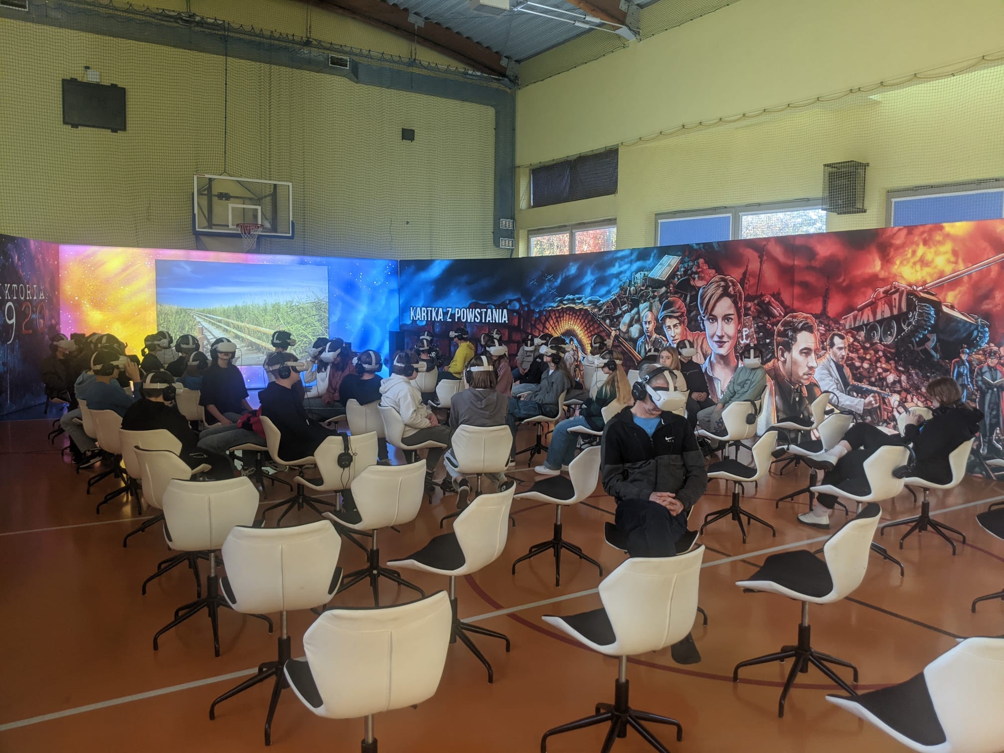 Uczniowie siedzą na krzesłach z założonymi googlami VR 