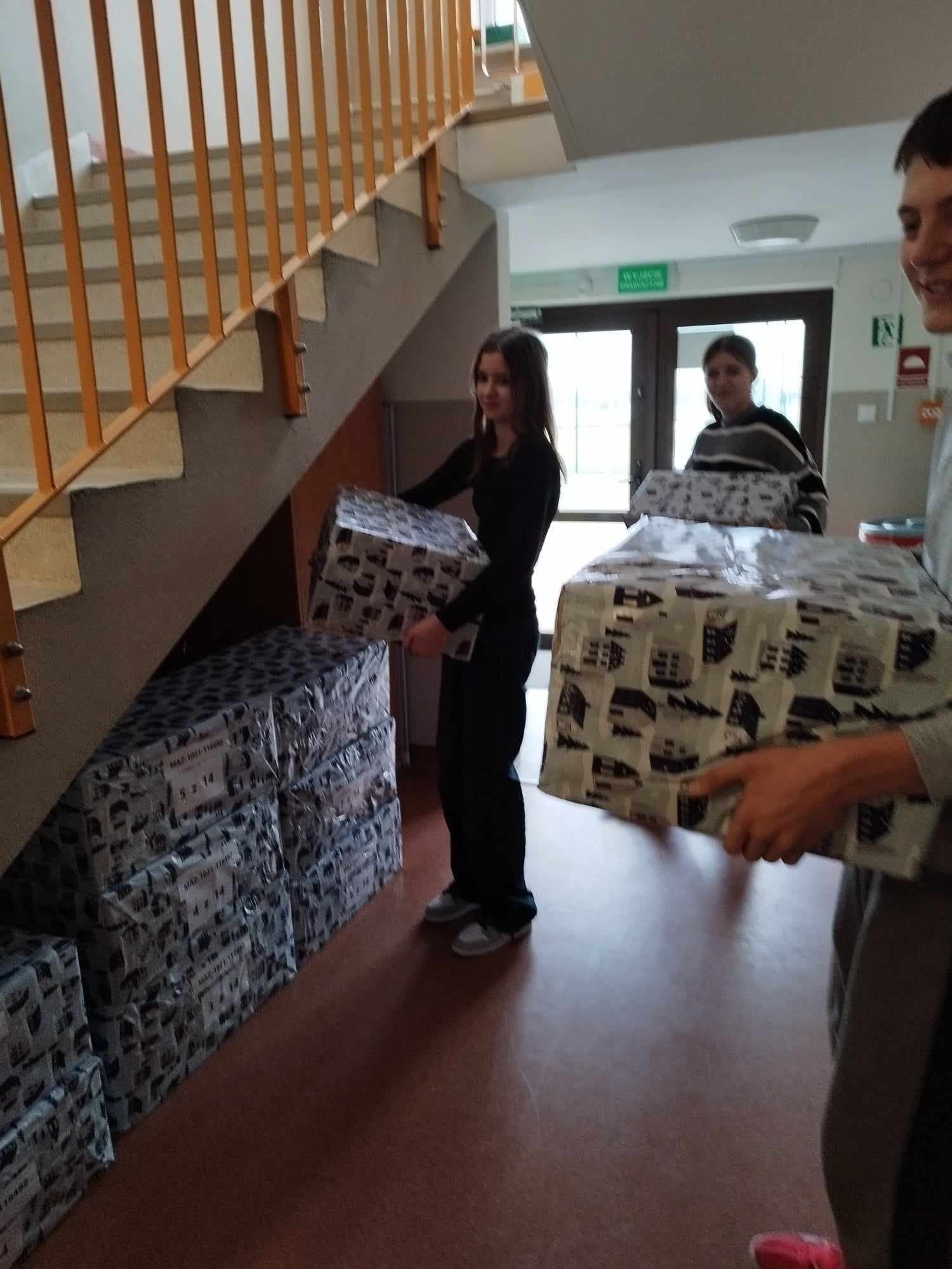 Uczniowie układają paczki na korytarzu