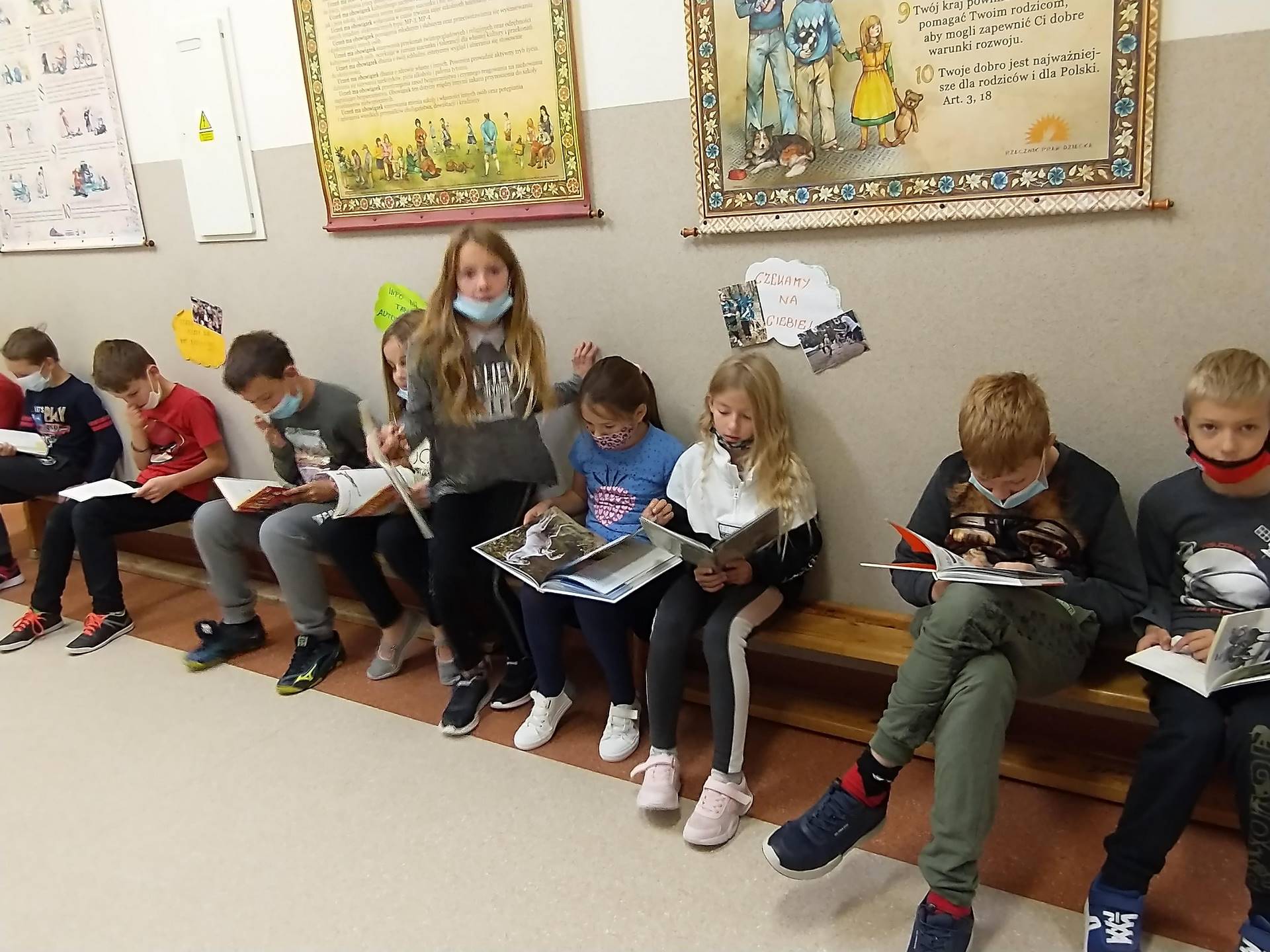 dzieci siedzą na ławce w szkole i czytają książki