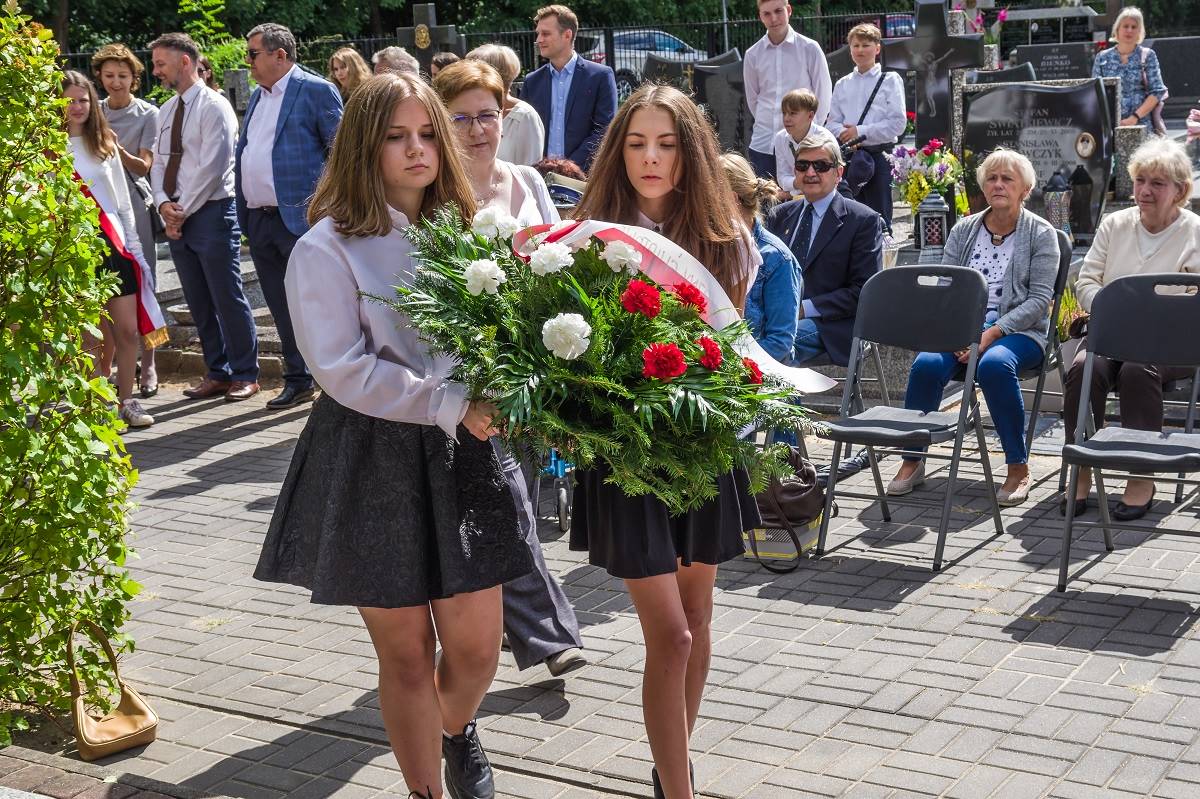 Uczennice składają kwiaty na grobie żołnierzy na cmentarzu w Skolimowie