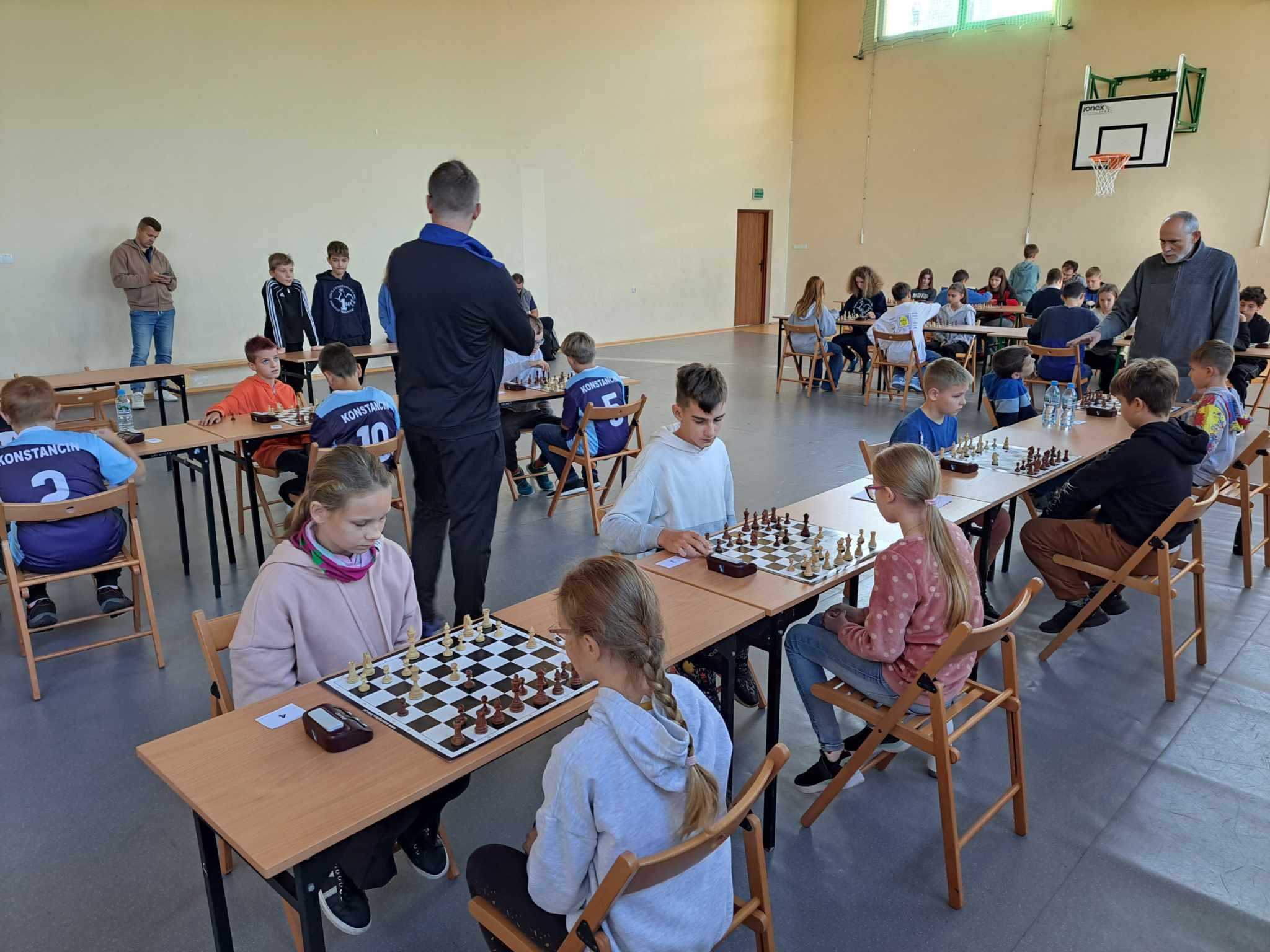 Dzieci siedzą przy stolikach i grają w szachy