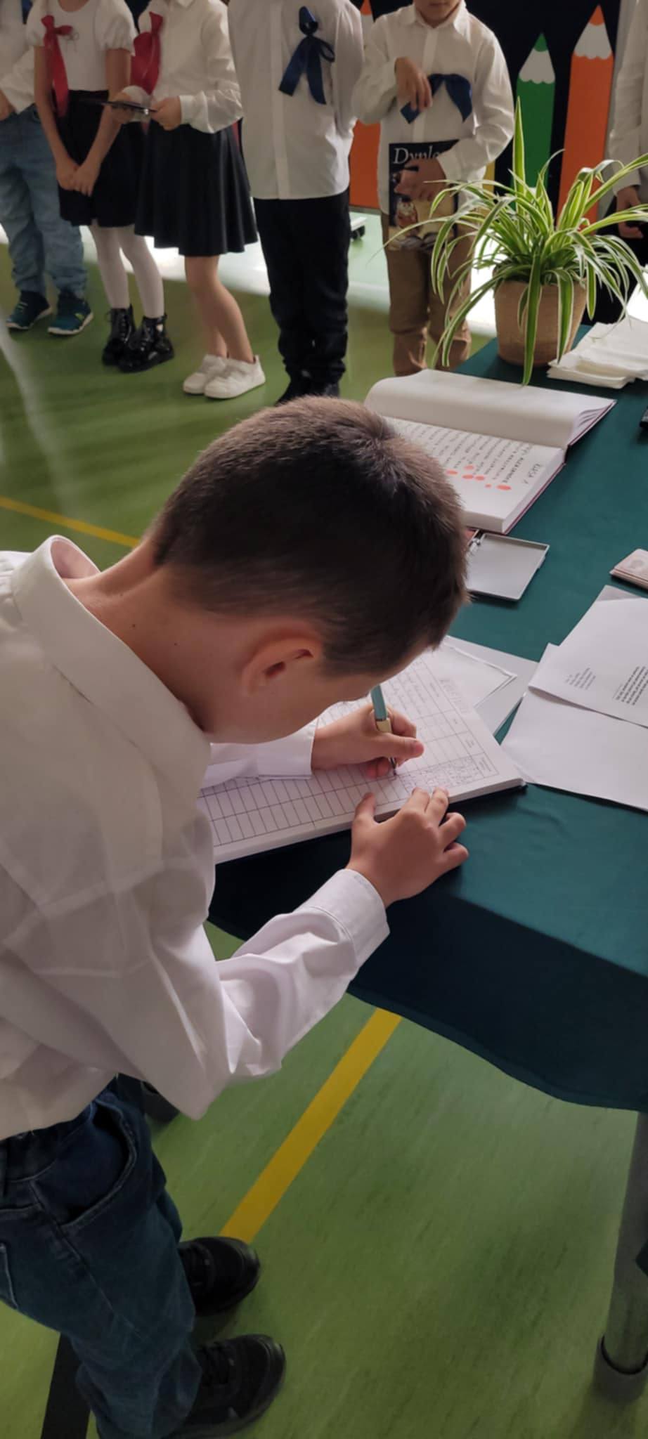 Uczeń wpisujący się do księgi pamiątkowej